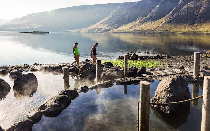 Visitors enjoying Hvammsvík Hot Spring with scenic mountain views near Reykjavík.