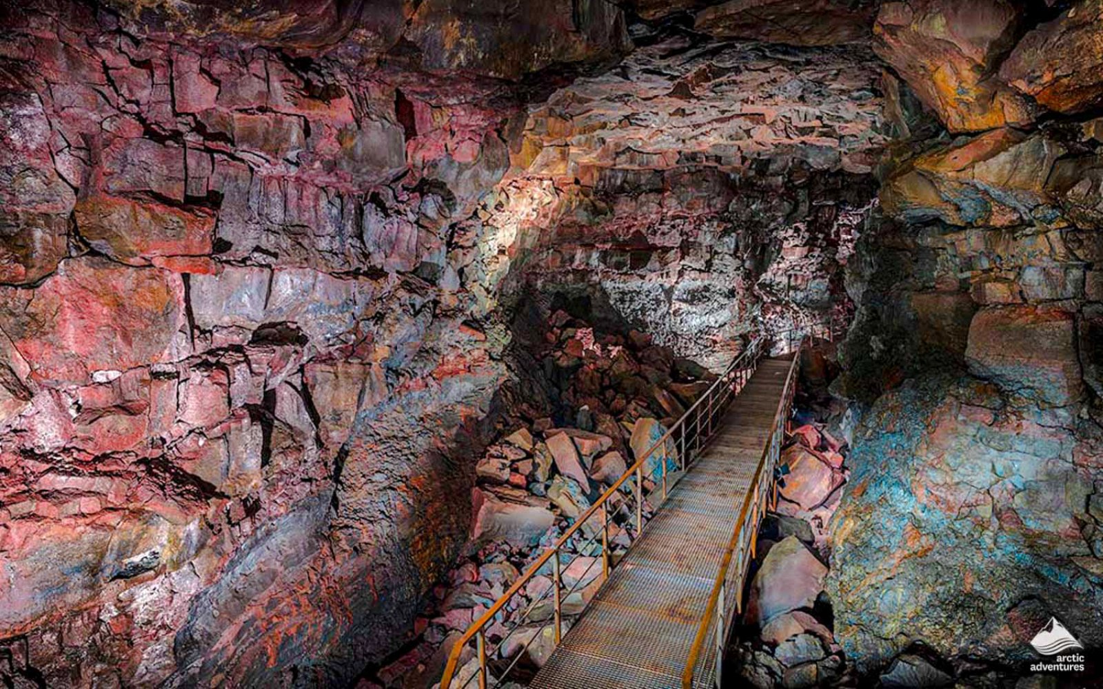 Raufarhólshellir Lava Tunnel interior with walkway and colorful rock formations.