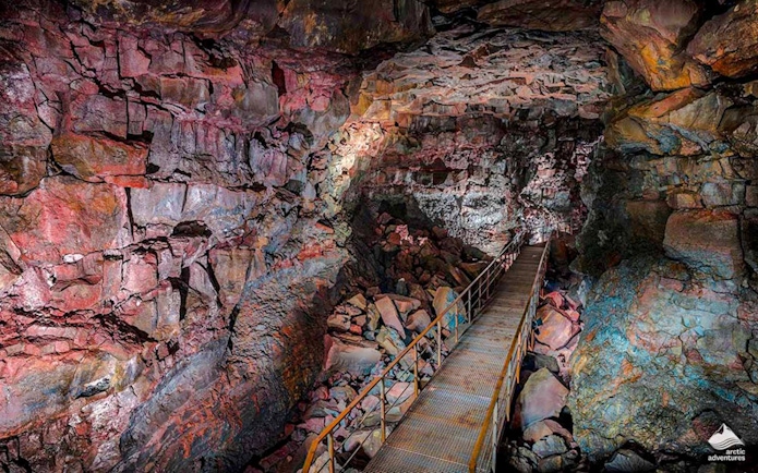 Raufarhólshellir Lava Tunnel interior with walkway and colorful rock formations.
