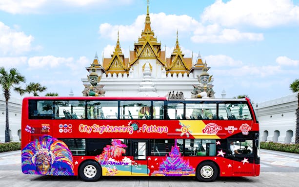 Pattaya Hop-On Hop-Off bus in front of a Thai temple with blue skies.