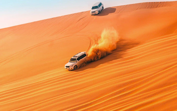 SUVs driving on sand dunes in Doha desert, Qatar.