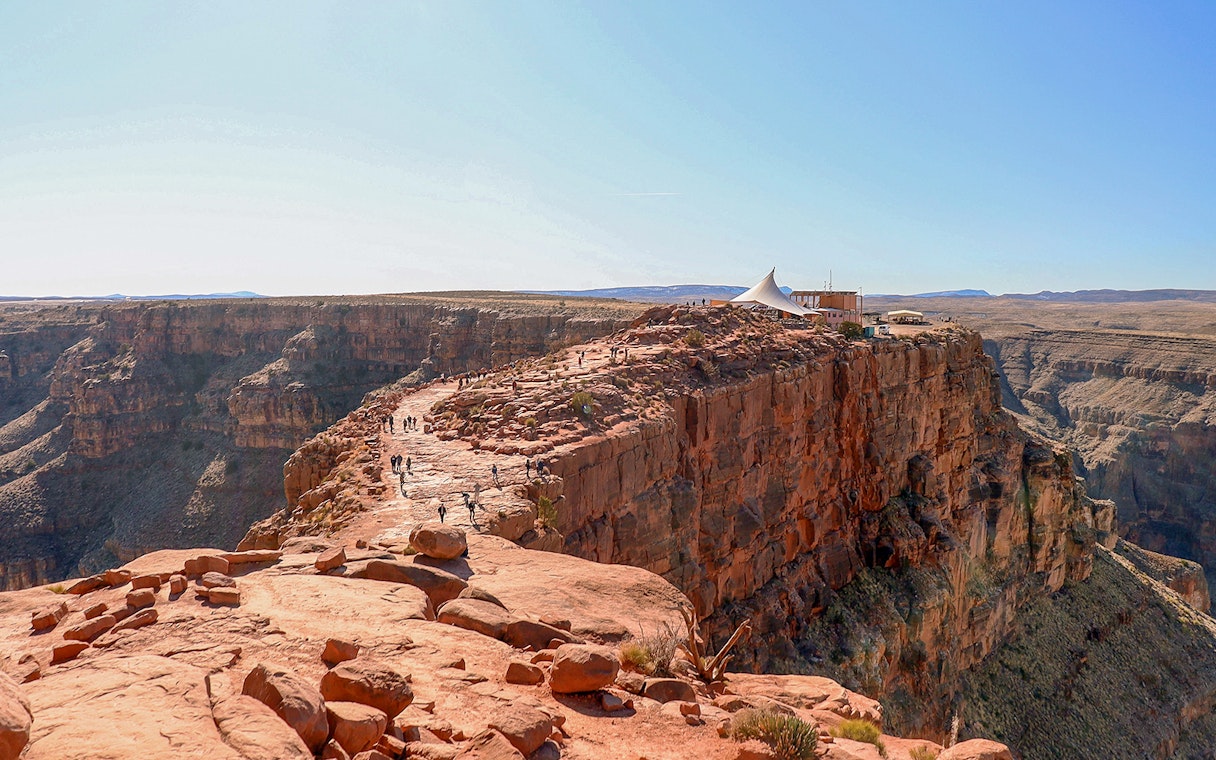 Grand Canyon West Rim with visitors walking along the cliff edge near a viewing platform.