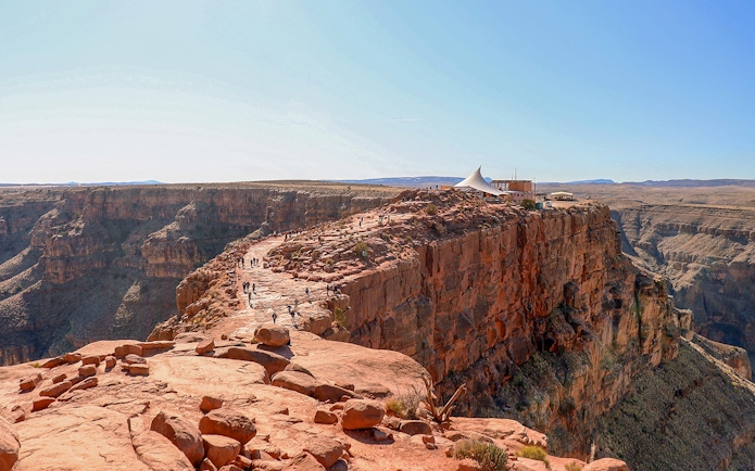 Grand Canyon West Rim with visitors walking along the cliff edge near a viewing platform.