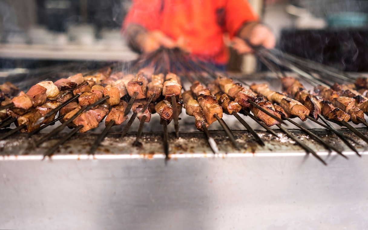 Grilled meat kebabs on skewers during a desert safari in Dubai.