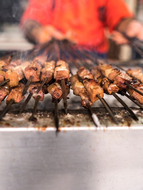 Grilled meat kebabs on skewers during a desert safari in Dubai.