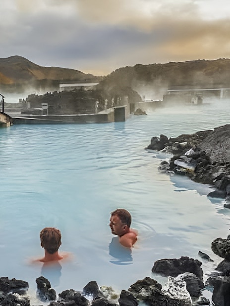 People relaxing in the Blue Lagoon geothermal spa with misty volcanic landscape, Iceland.
