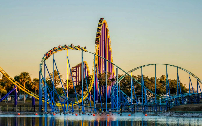 Roller coaster at SeaWorld San Antonio with vibrant loops and tracks over water.