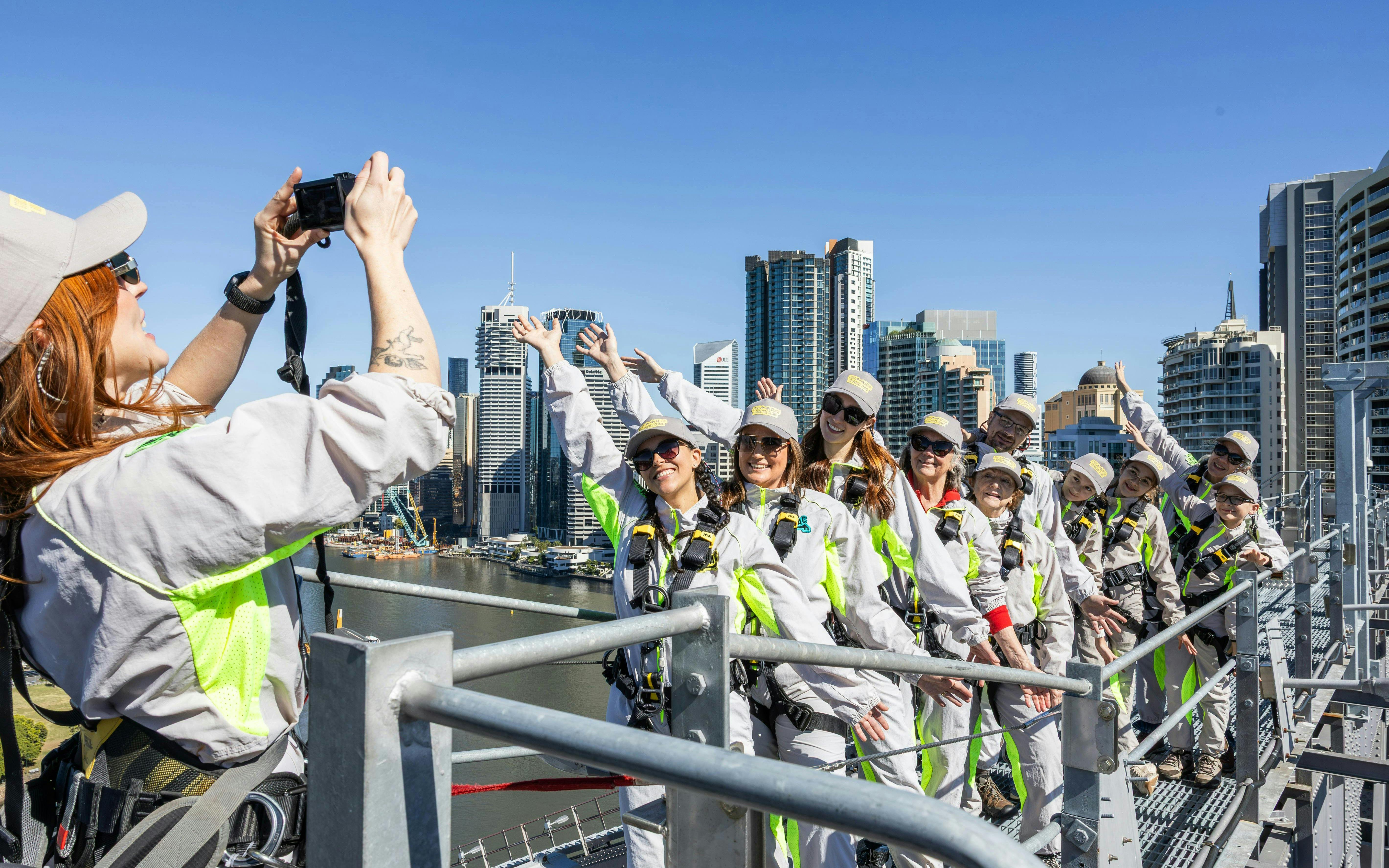 Group climbing Story Bridge in Brisbane with city skyline in background.