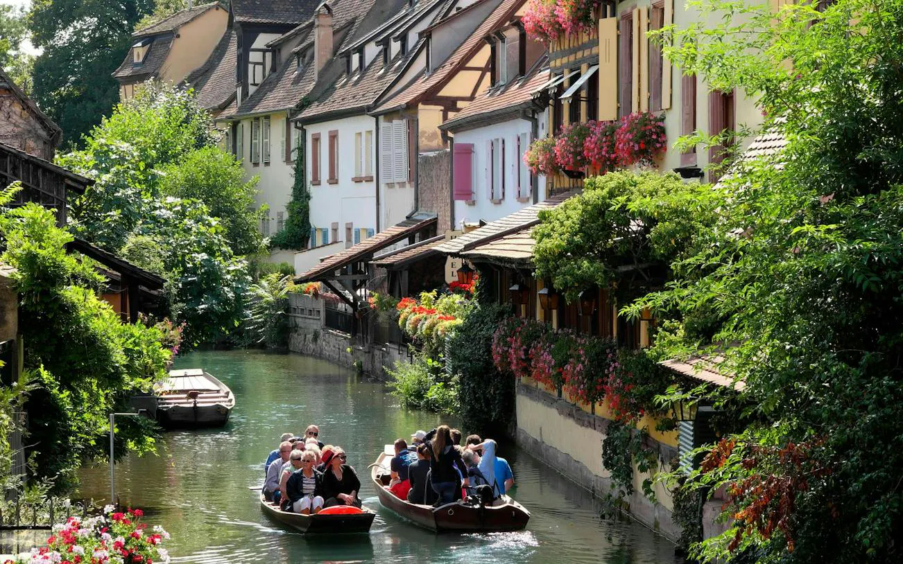Boat tour along canal with medieval houses in Colmar, showcasing architectural charm.