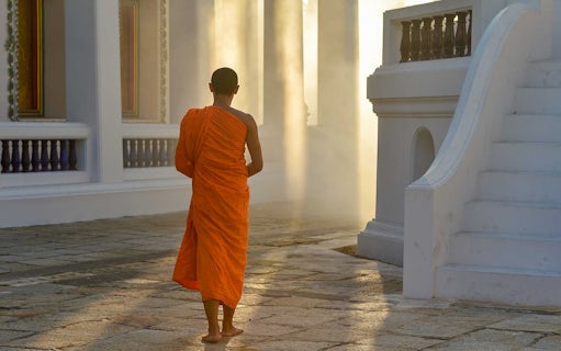Monk in orange robe walking at Marble Temple, Bangkok.
