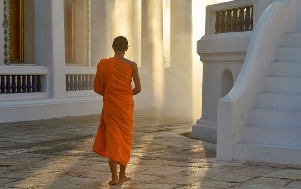 Monk in orange robe walking at Marble Temple, Bangkok.