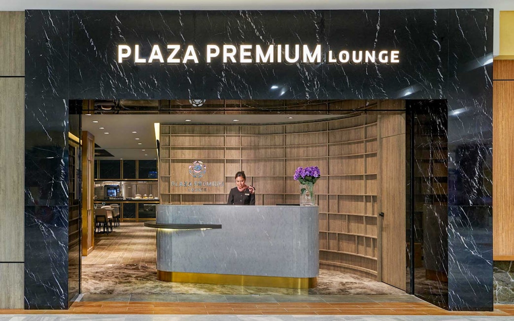 Plaza Premium Lounge entrance with reception desk and staff member.