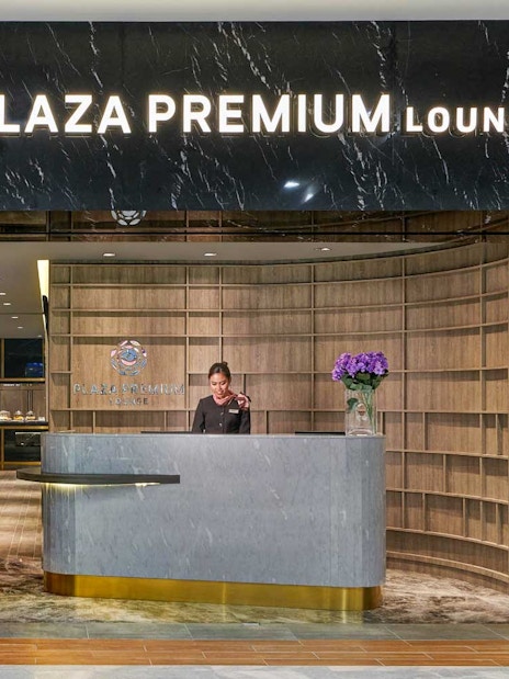 Plaza Premium Lounge entrance with reception desk and staff member.
