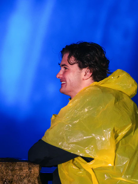 Person in yellow poncho enjoying Niagara Falls illuminated at night.