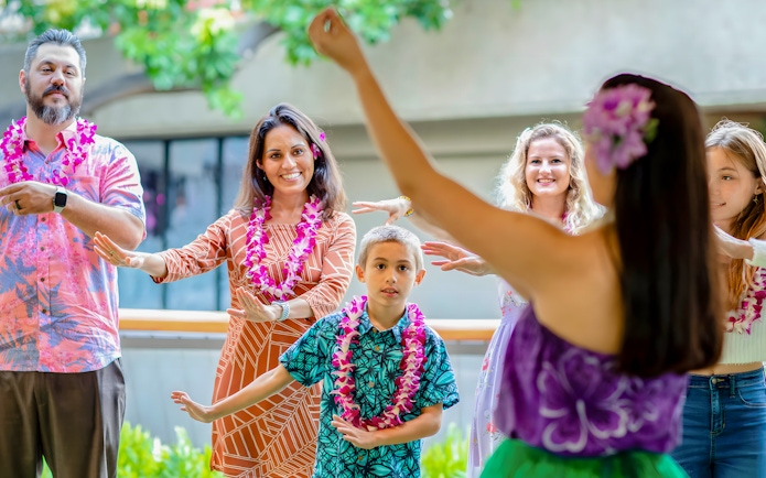 Guests learning hula dance from instructor before Rock-A-Hula show in Hawaii.