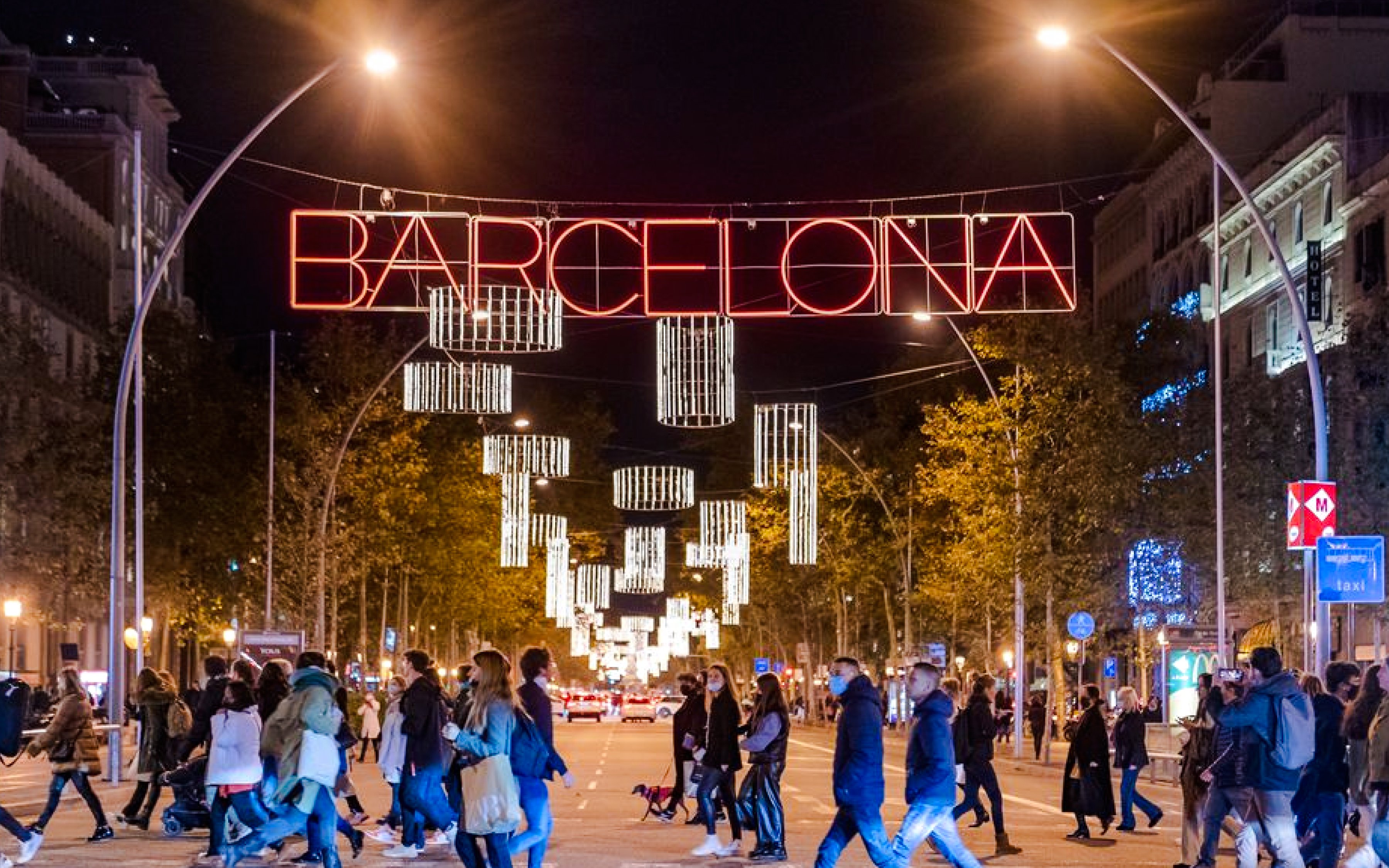 Crowd walking under festive lights on a Barcelona street during Christmas.