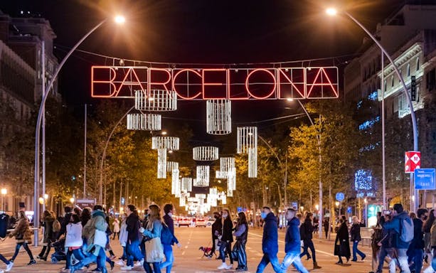 Crowd walking under festive lights on a Barcelona street during Christmas.