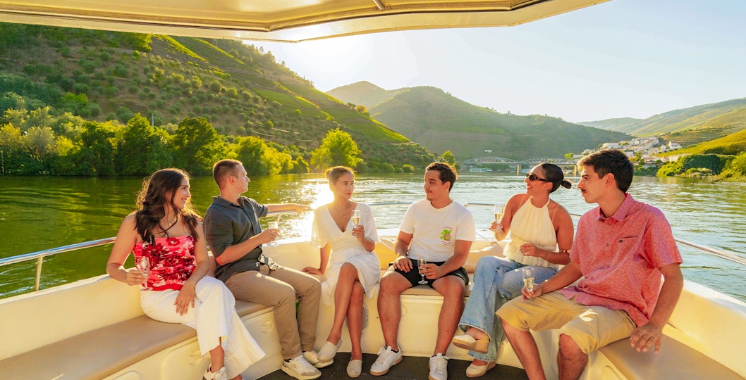 Tourists enjoying a boat ride on the Douro River in Douro Valley at sunset.