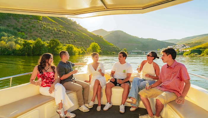 Tourists enjoying a boat ride on the Douro River in Douro Valley at sunset.