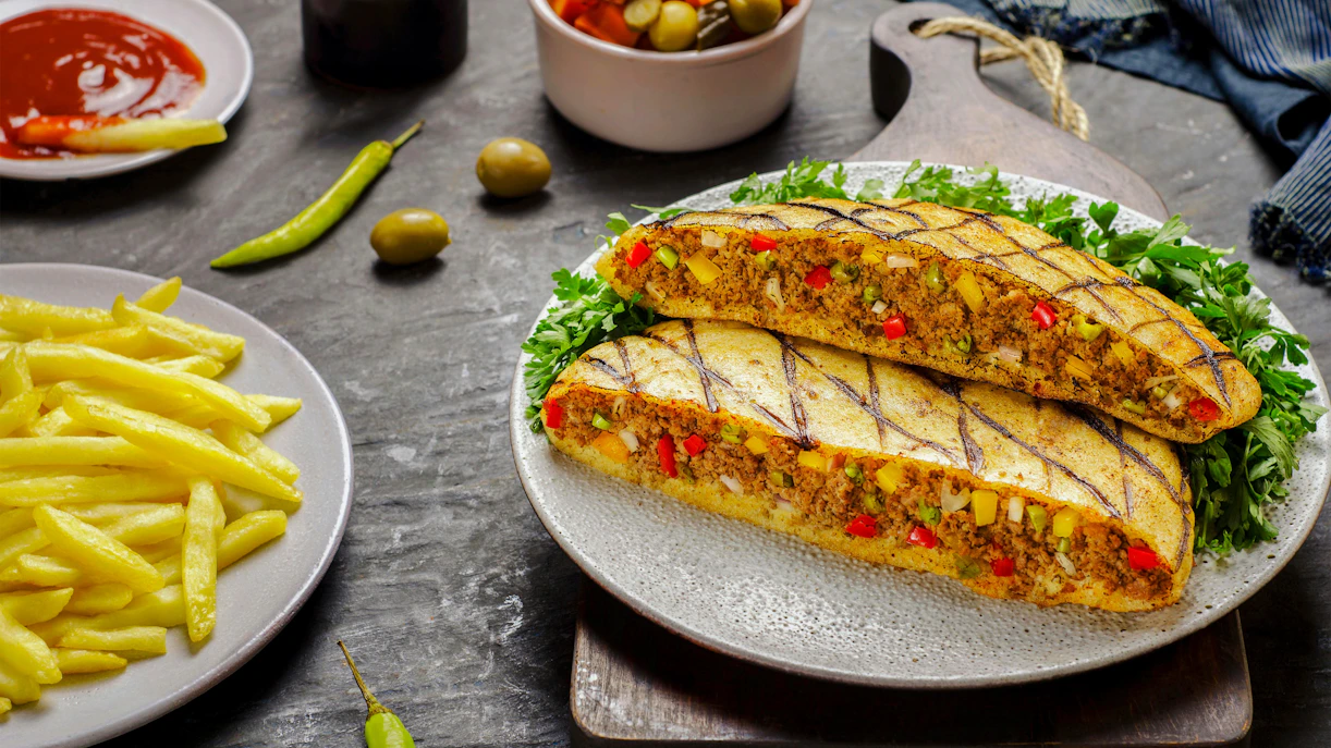 Traditional Egyptian hawawshi with minced meat and vegetables on a plate with fries.