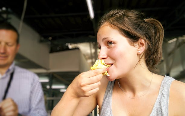 Woman enjoying local dish on Penang street food tour.