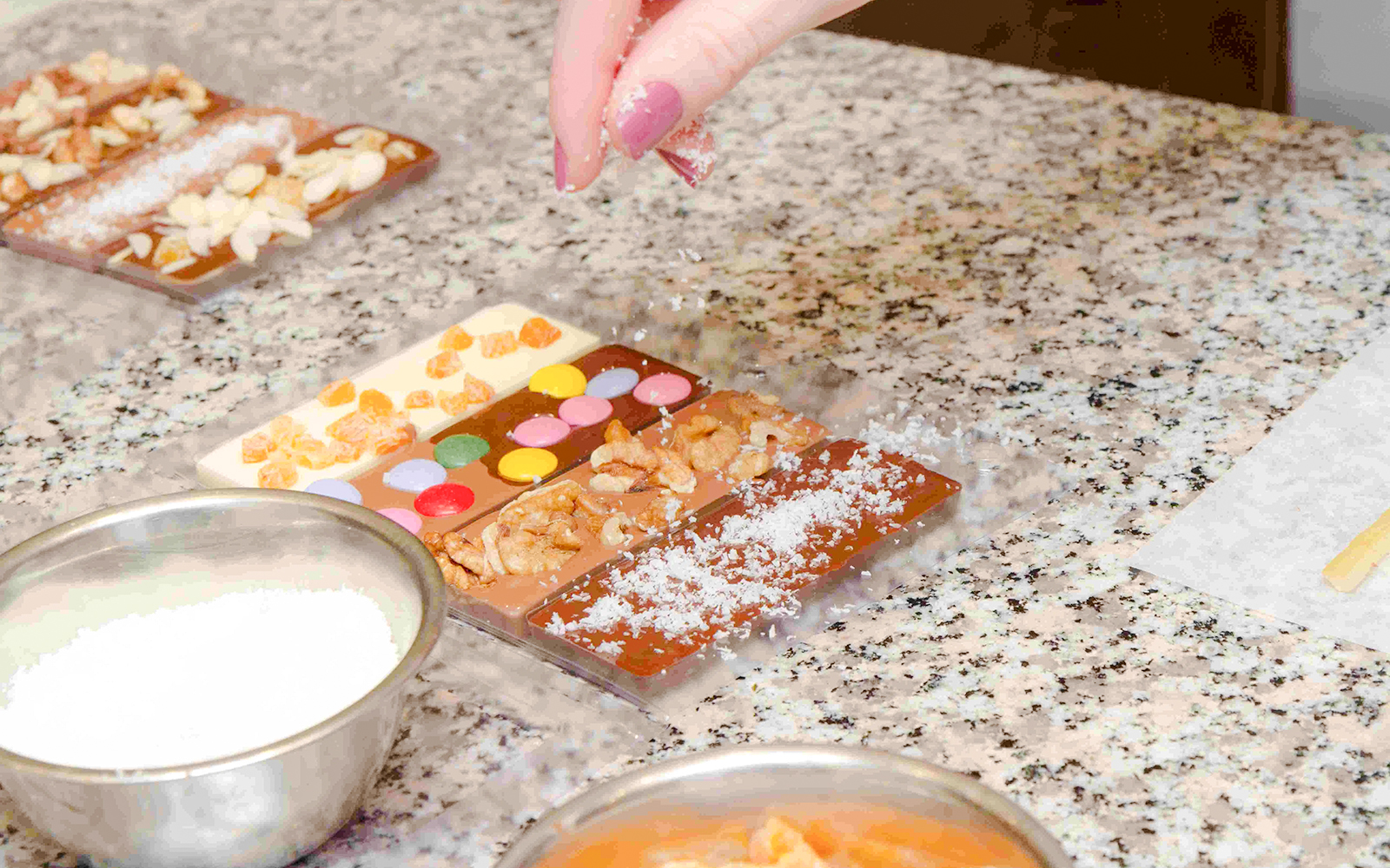 Hand decorating chocolate bars with nuts and candies at Choco-Story Paris.
