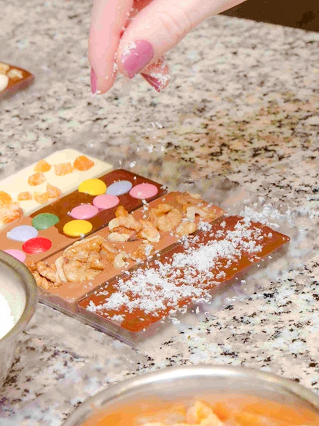 Hand decorating chocolate bars with nuts and candies at Choco-Story Paris.