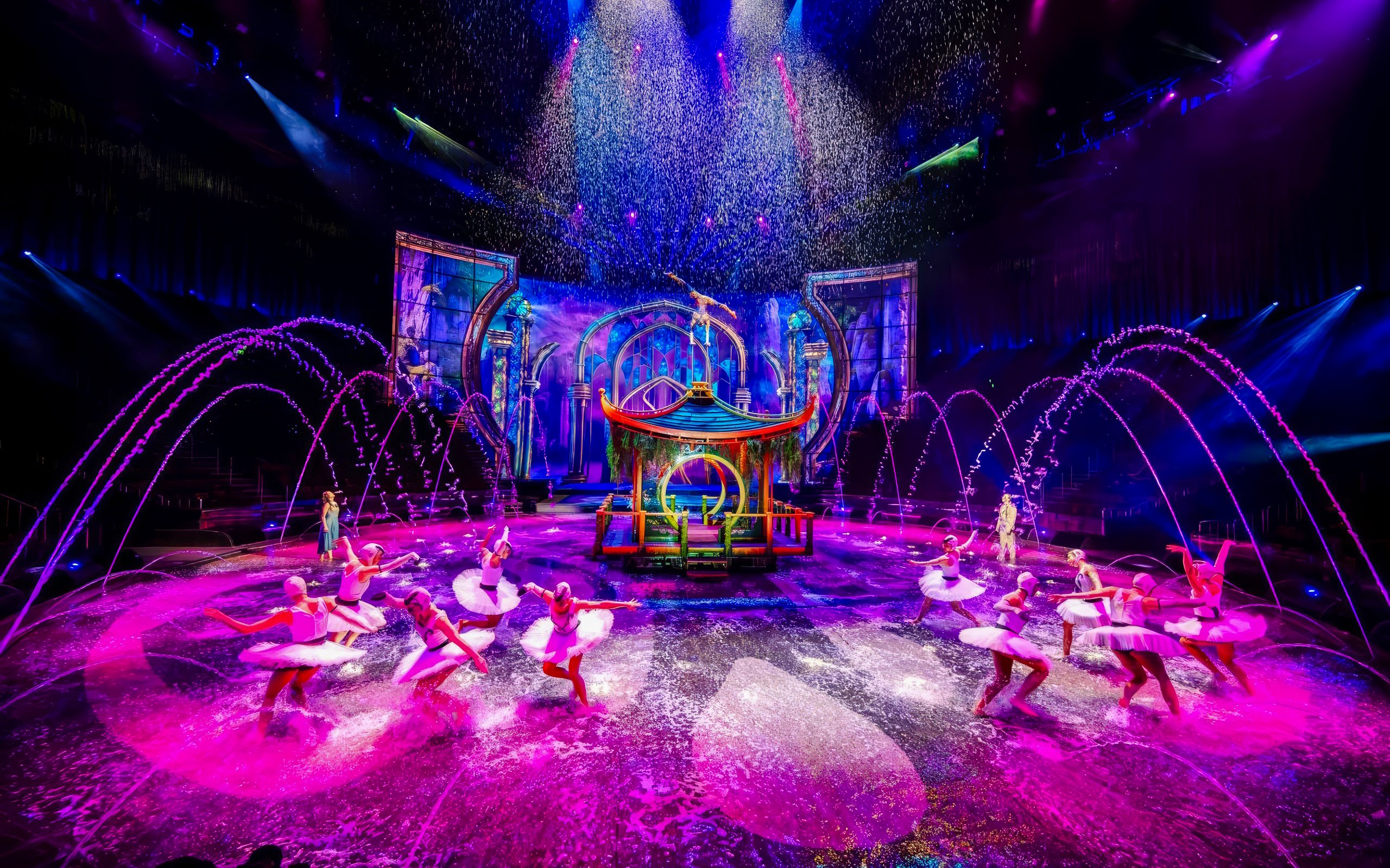 Performers at House of Dancing Water Show with colorful stage and water effects.