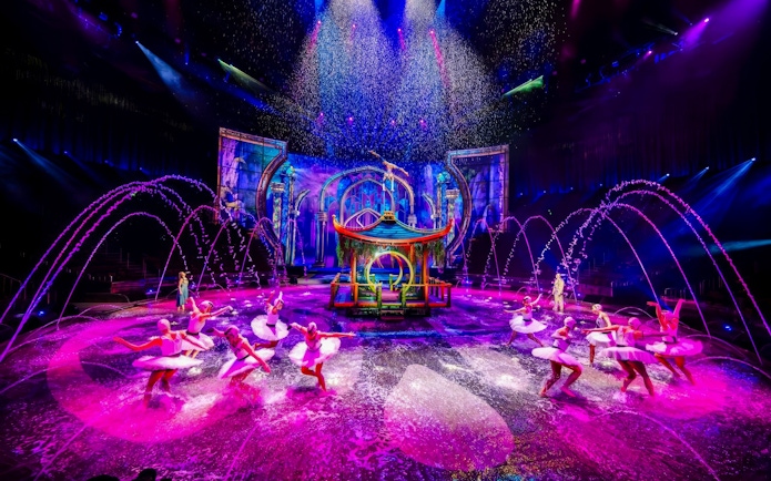 Performers at House of Dancing Water Show with colorful stage and water effects.