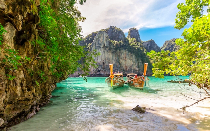 Longtail boats on Maya Bay beach, Bamboo Island, Phi Phi with limestone cliffs.