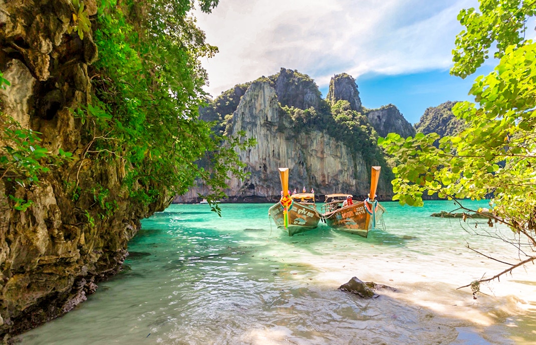 Longtail boats on Maya Bay beach, Bamboo Island, Phi Phi with limestone cliffs.
