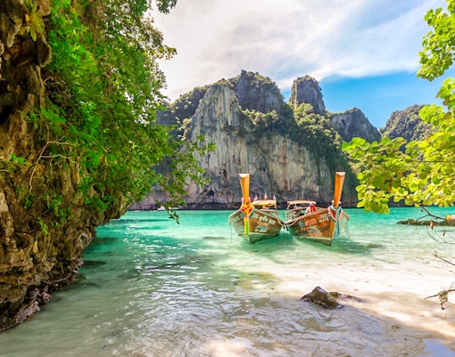 Longtail boats on Maya Bay beach, Bamboo Island, Phi Phi with limestone cliffs.