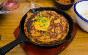 Traditional Spanish tortilla with sauce in a skillet at a Santiago restaurant.