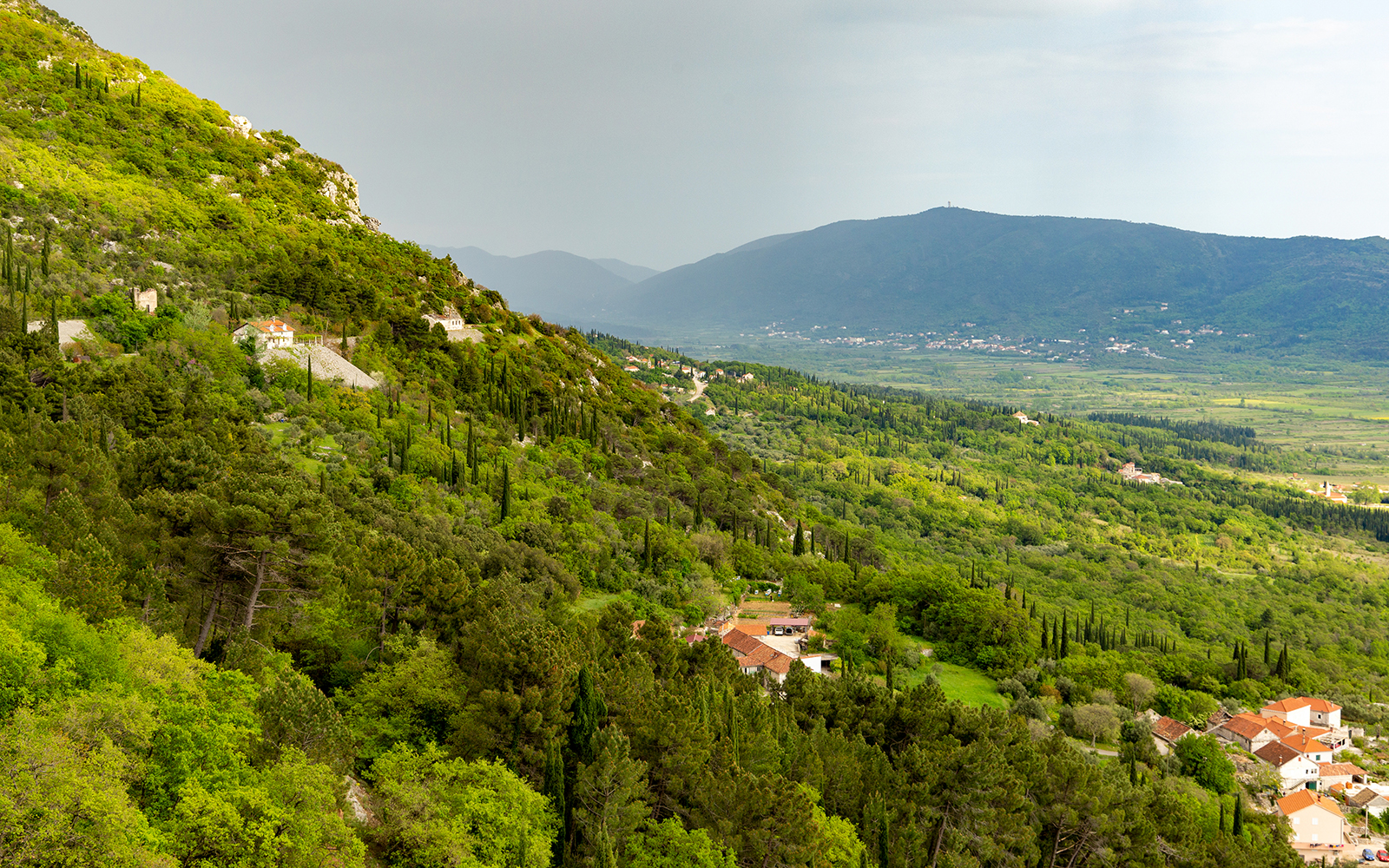 Scenic view of lush green hills and distant mountains near Kotor, Montenegro.
