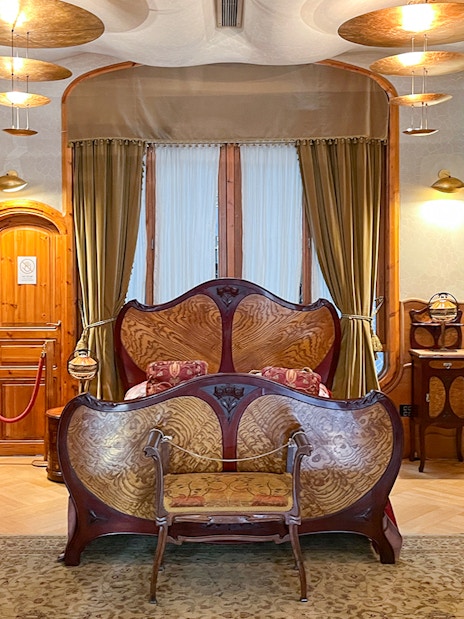 Casa Batlló bedroom with ornate wooden bed and decorative furnishings in Barcelona.