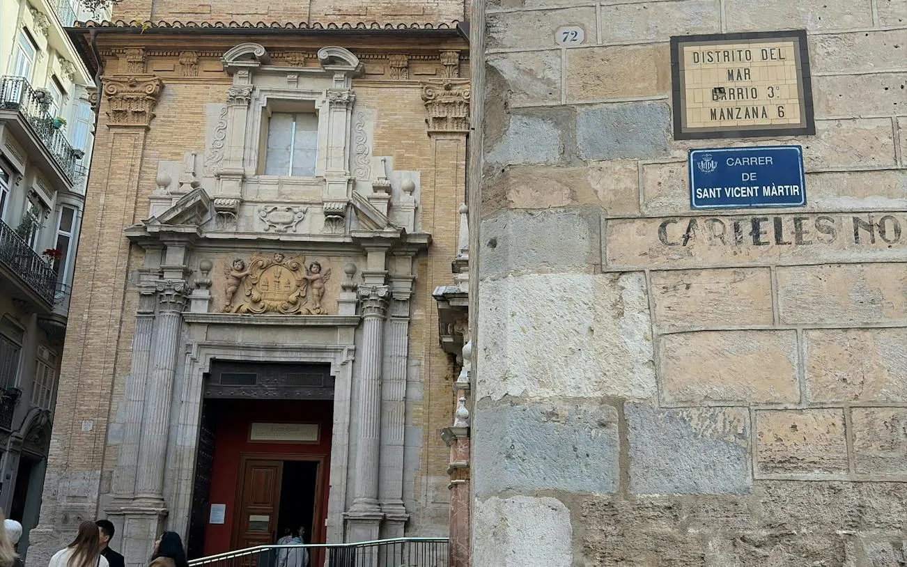 Valencia street view with historic building entrance and signs for self-guided city exploration game.