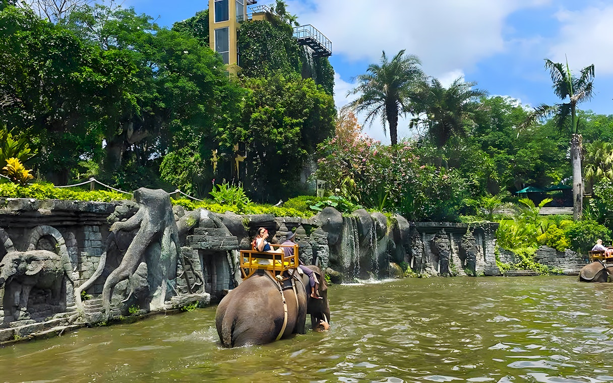 Girl riding an elephant through water at Bali Zoo Elephant Expedition.