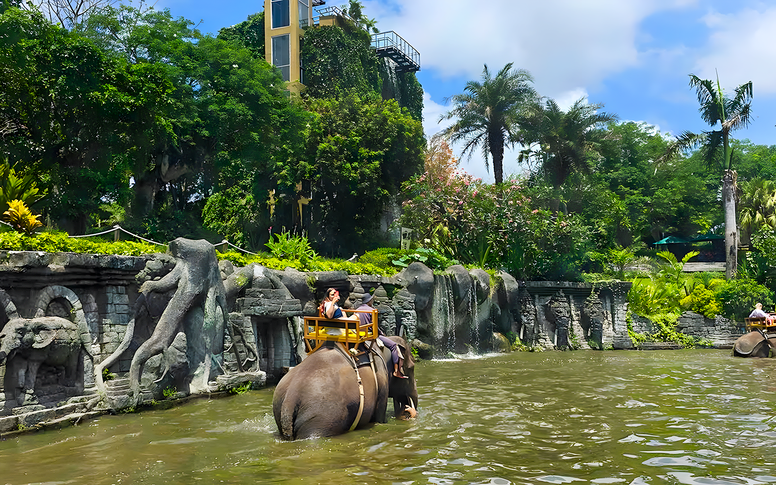 Girl riding an elephant through water at Bali Zoo Elephant Expedition.