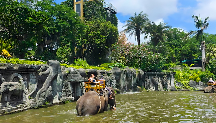 Girl riding an elephant through water at Bali Zoo Elephant Expedition.