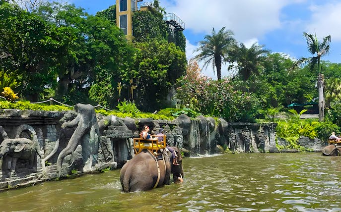 Girl riding an elephant through water at Bali Zoo Elephant Expedition.