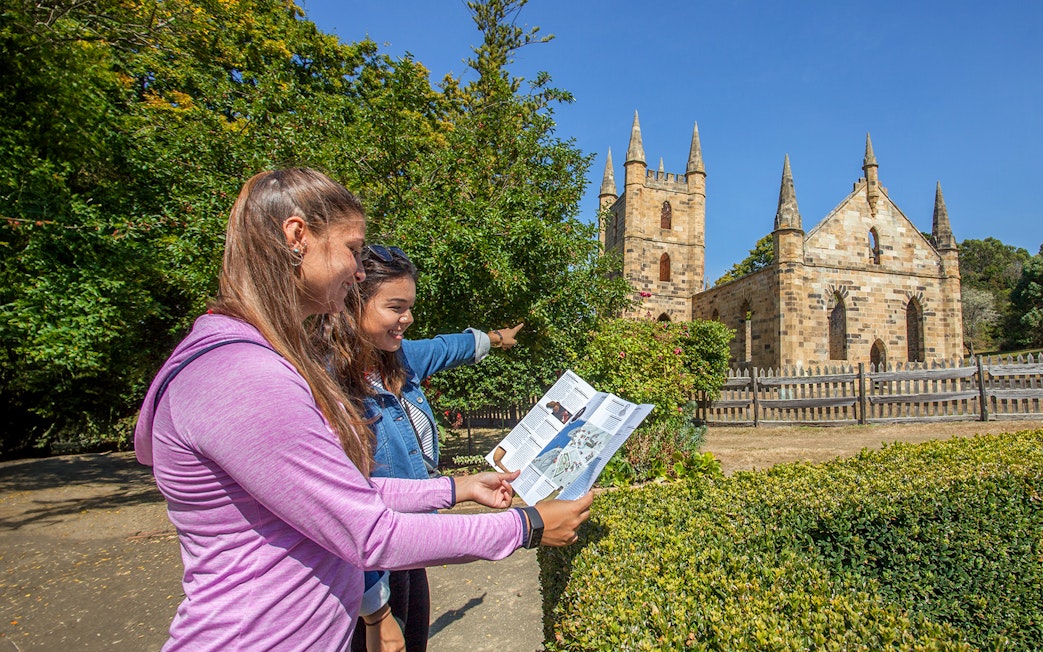Visitors exploring Port Arthur Historic Site with a map, Tasmania.