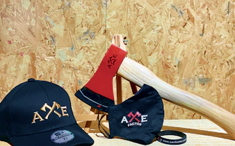 Axe Factor merchandise including a cap, mask, and axe on a wooden background.
