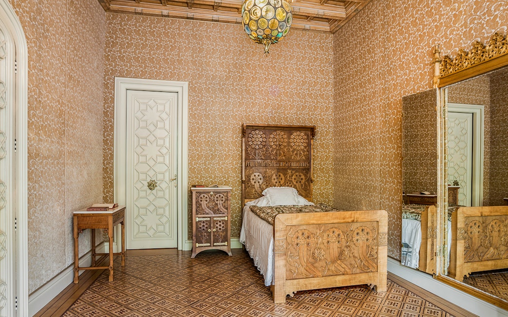 Casa Amatller bedroom with ornate wooden bed and patterned wallpaper.