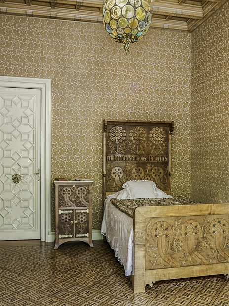 Casa Amatller bedroom with ornate wooden bed and patterned wallpaper.