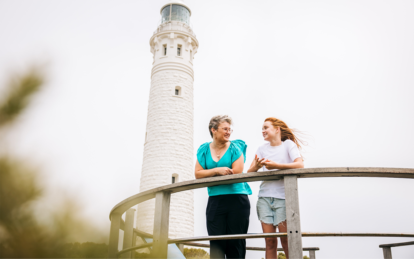 Two women on boardwalk with Cape Leeuwin Lighthouse in background.