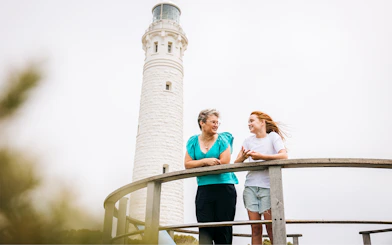 Two women on boardwalk with Cape Leeuwin Lighthouse in background.