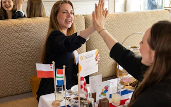 High-five at a table with Dutch flags and traditional snacks in Amsterdam.