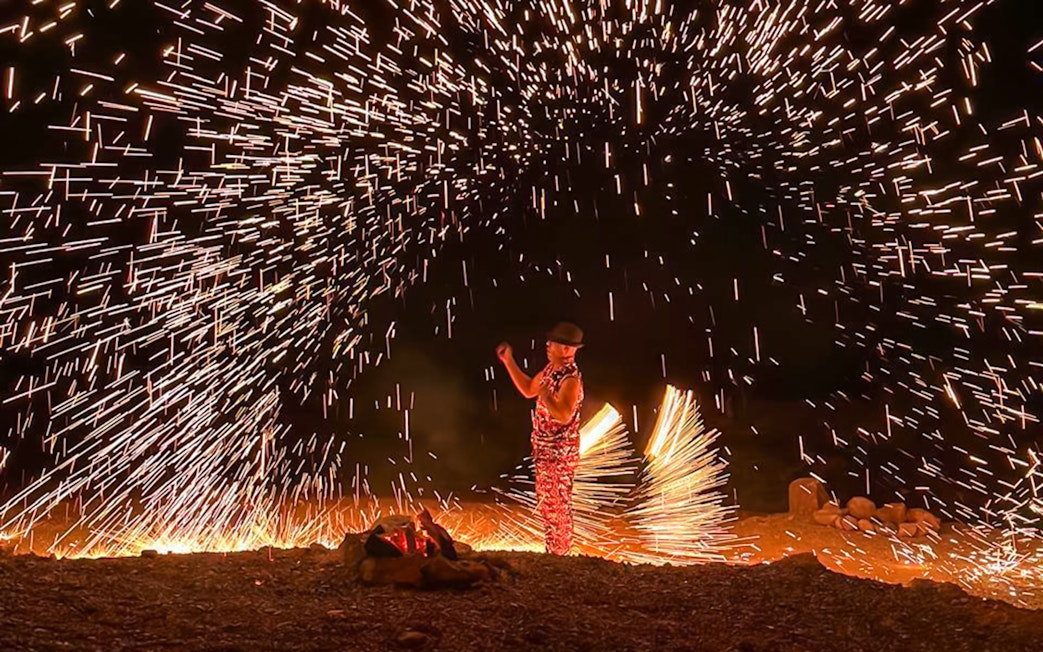 Performer with fire sparks at night show, Marrakesh desert camping Agafay.