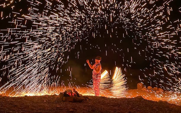 Performer with fire sparks at night show, Marrakesh desert camping Agafay.
