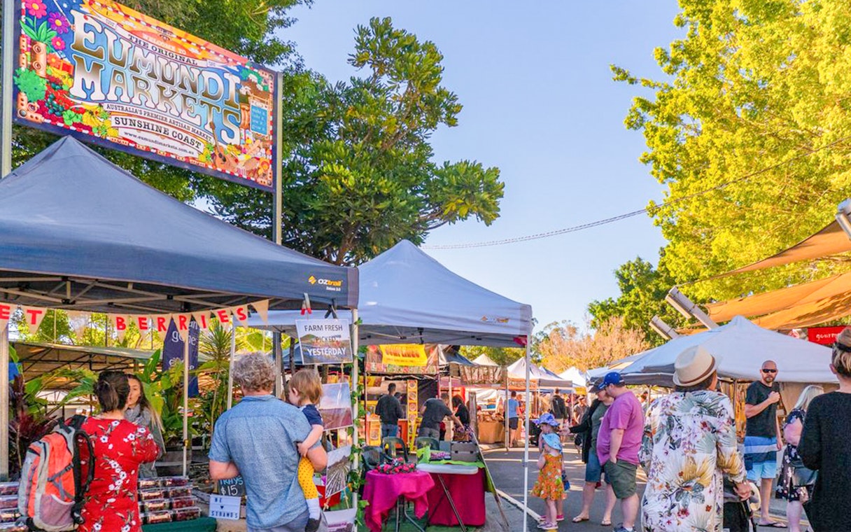 Eumundi Markets entrance with visitors exploring stalls on the Sunshine Coast.